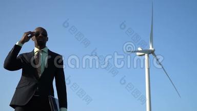 穿商务西装的黑人戴着太阳镜，靠近风力发电机的背景